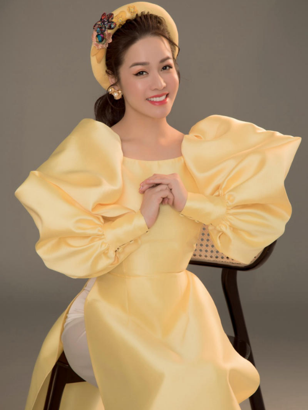 Áo dài cổ vuông khoe khéo xương quai xanh, cao ráo thon gọn, quyến rũ khi kết hợp sắc vàng. Vàng nghệ hoặc vàng đồng cho tiệc tối, vàng nhạt cho sự kiện ban ngày.